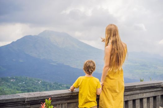 Mom and son tourists on background looking at Batur volcano. Indonesia. Traveling with kids concept.