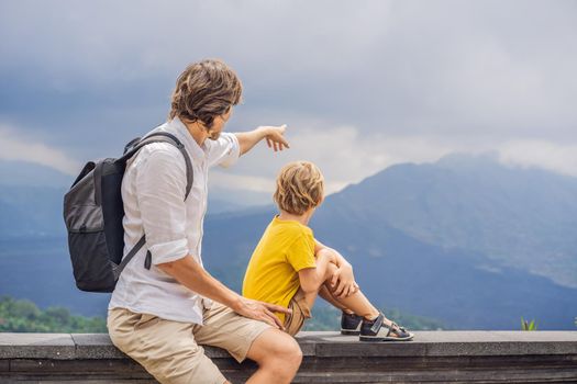 Dad and son tourists on background looking at Batur volcano. Indonesia. Traveling with kids concept.