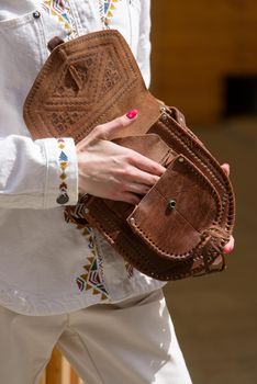 small brown women's leather bag with a carved pattern. street photo