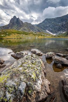 the stunning landscape on the mountain lake with a big rock. Vertical view