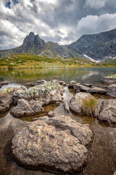 beauty day landscape on the mountain lake with rocks at the front. Vertical view