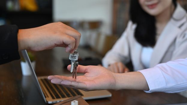 Cropped shot young couple receiving keys from real estate agent. New house, insurance and real estate concept.