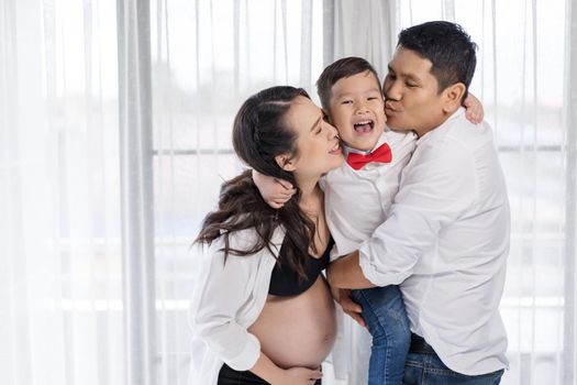 happy family concept, pregnant mother and father kissing kid boy 