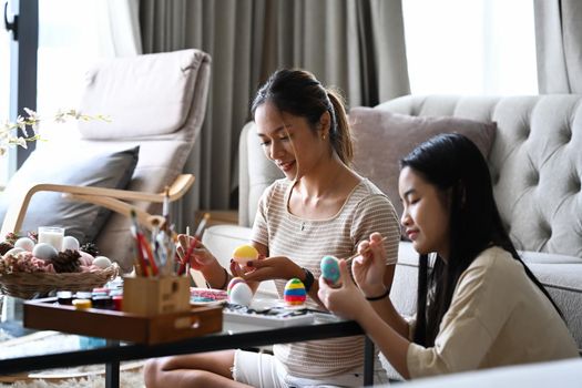 Attractive young woman with little cute girl are preparing for Easter festival at home.