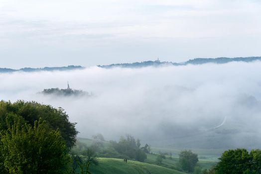 Cloudy scenery in the Julian Alps in Slovenia, church hidden in the fog