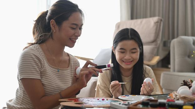 Happy family painting Easter eggs together while sitting in bright living room. Easter holidays and people concept.