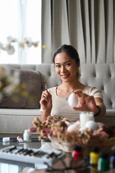 Attractive young woman enjoy coloring and painting Easter eggs. Easter concept.
