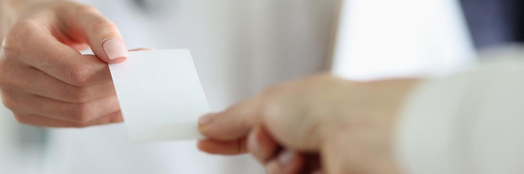 Doctor's hands hold out the document to the patient, mockup. Close-up of female hands. Receipt for payment of the service, prescription to the pharmacy