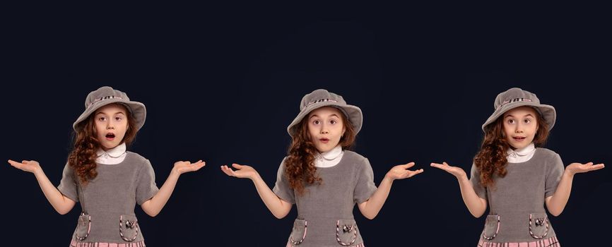 Close-up portrait of a beautiful curly little girl in a gray dress and hat looking wondered while posing on a black studio background. Set of people sincere emotions, lifestyle concept. Mockup copy space.