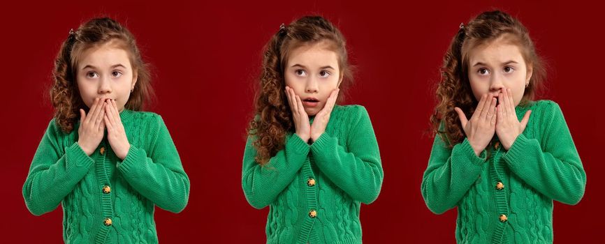 Close-up portrait of a lovely curly child in a green knitted sweater looking wondered and scared while posing on a red studio background. Set of people sincere emotions, lifestyle concept. Mockup copy space.