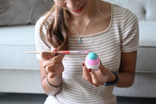 Young woman enjoy painting a water colors on eggs for Easter festival.