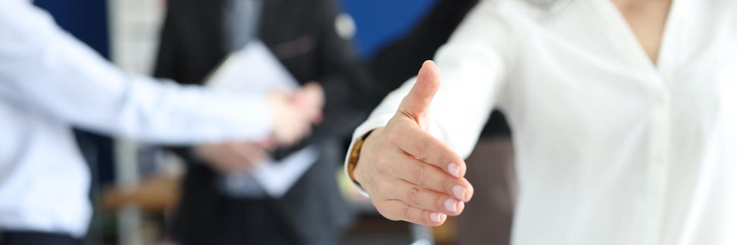 Beautiful smiling business woman stretches out her hand in the office. Greeting partners to business at a meeting, cooperation