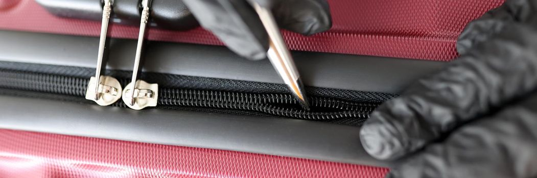 Gloved hands mending a snake on a suitcase, close-up. Shoemaker tailor tool for repairing snake on bags and clothes, tailor shop