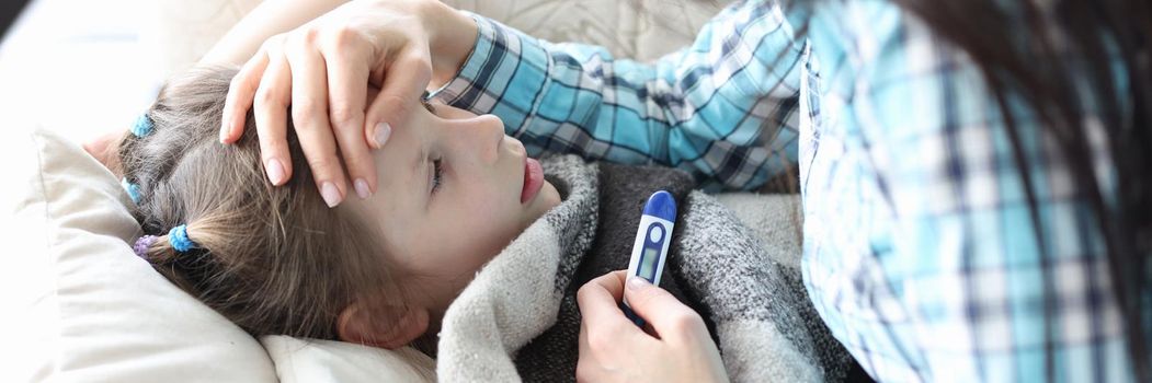 Caring mother touches the forehead of a sick girl, close-up. Temperature measurement in a girl, pademia covid