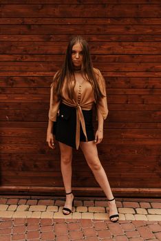 Ukrainian young woman in a mini skirt. Fashion summer 2021 style glamorous. Brown wooden striped background.