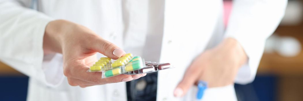 A female doctor in uniform holds capsules in a blister in her hands. Pharmaceft in the pharmacy offers bio food supplements