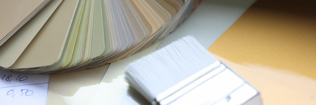 Samples of a color palette and a paint brush lie on the table, close-up. Beautiful color scheme for design, designer workspace