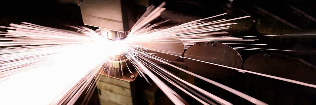 Bright sparks from metal welding in production, close-up. Factory machine, industrial equipment, workplace
