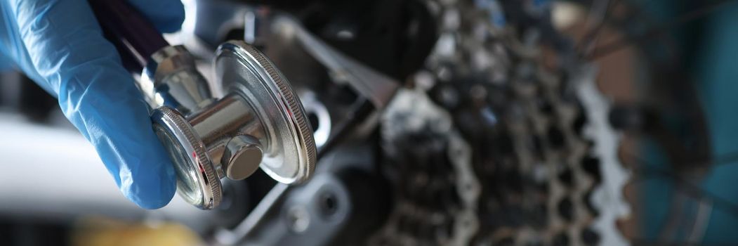 A hand in a glove holds a wrench for adjusting the bike, a bicycle chain close-up. Repair and maintenance and cleaning of bicycle parts