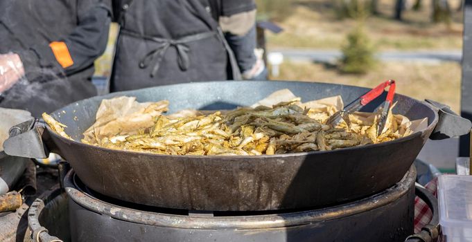 Smelt fish is fried on a large grill during the fish festival in Svetlogorsk Raushen, Kalinigrad region, Russia, near the Baltic sea. High quality photo.