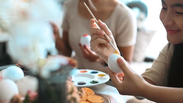 Cheerful asian girl painting Easter eggs at home. Easter, holidays and people concept.