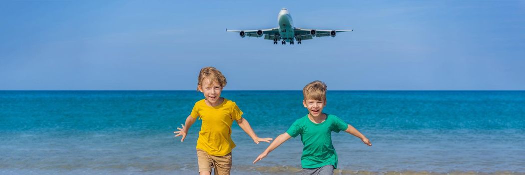 Two happy boys have fun on the beach watching the landing planes. Traveling on an airplane with kids concept. Text space. Island Phuket in Thailand. Impressive paradise. Hot beach Mai Khao. Amazing landscape. BANNER, LONG FORMAT