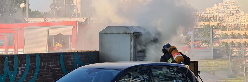 During the day, a firefighter runs down the street to the source of the fire. Danger of spreading fire. Smoke in the city