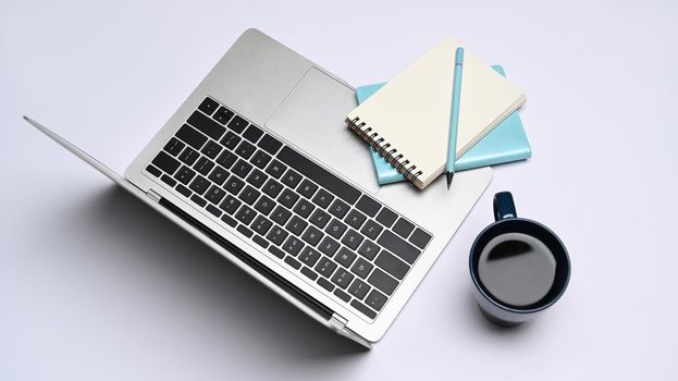 Laptop computer, notebook and coffee cup on white background. Top view.