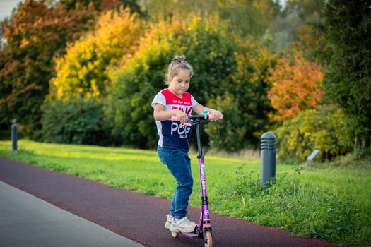 In summer, a girl rides a scooter in the park. Russia Moscow September 24, 2020.