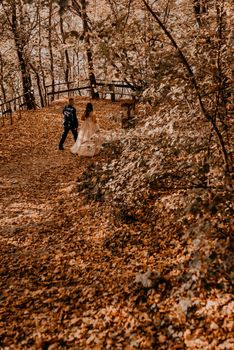 wedding couple in love man and woman walking in autumn forest. groom in suit and bride in dress with crown on head.