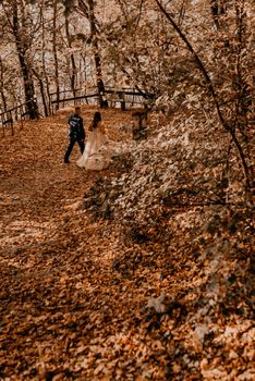 wedding couple in love man and woman walking in autumn forest. groom in suit and bride in dress with crown on head.