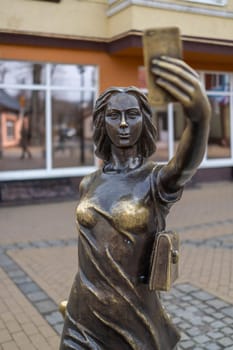 Bronze statue monument: a modern girl with a smartphone in her hand takes a selfie in Zelenogradsk, Kaliningrad region, Russia, near the Baltic sea.