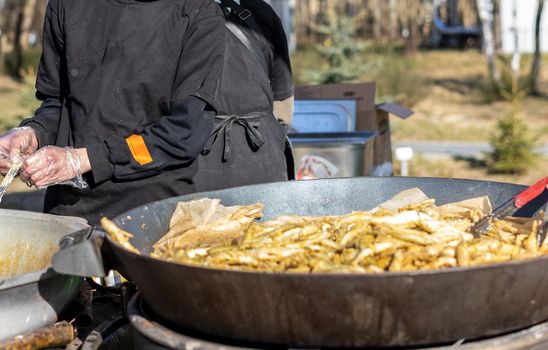 Smelt fish is fried on a large grill during the fish festival in Svetlogorsk Raushen, Kalinigrad region, Russia, near the Baltic sea. High quality photo.
