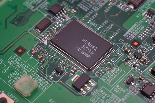 Electronic components. Integrated circuits, resistors, transistors and capacitors on PCB. Green copper board detail. Standard color code. Old computer hardware.