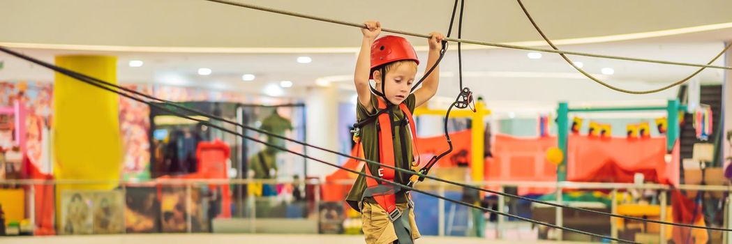 Adorable little boy enjoying his time in climbing adventure park in the mall. BANNER, LONG FORMAT