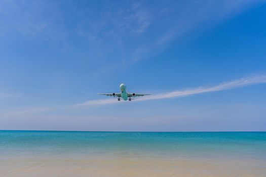 A white airplane flying in a clear pale blue sky.