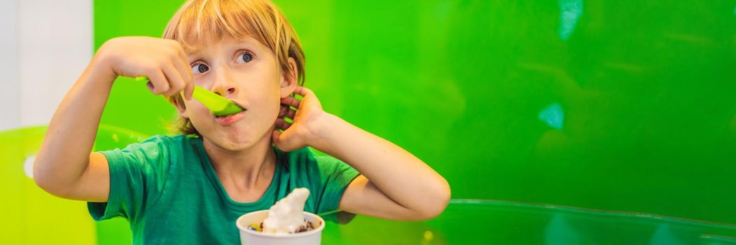 Happy young boy eating a tasty ice cream or frozen yogurt. BANNER, LONG FORMAT