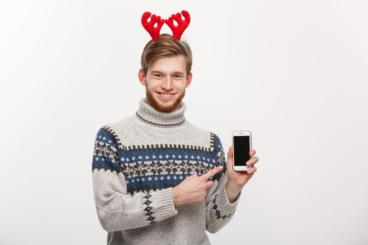 Holiday and Business Concept - Young handsome man showing mobile phone display and pointing finger presenting.