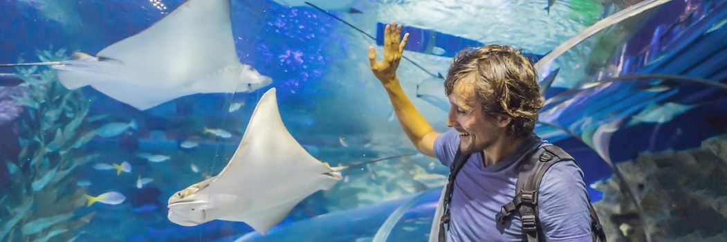 curious tourist watching with interest on shark in oceanarium tunnel. BANNER, LONG FORMAT