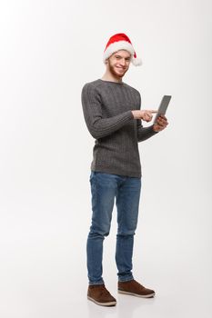 Holiday concept - Young beard handsome man working on digital tablet over white background.