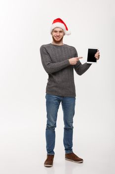 Holiday and Business Concept - Young handsome man showing tablet display and pointing finger presenting.