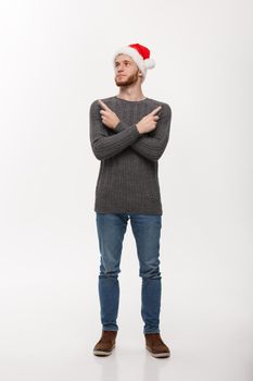 Holiday Concept - Young beard man in sweater enjoy playing and pointing finger upward.