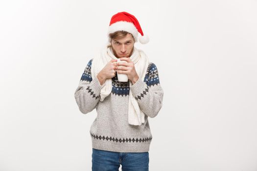 Christmas concept - Young beard man in sweater and santa hat holding a hot coffee cup isolated on white with copy space.