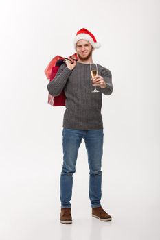 Christmas Concept - Young handsome beard man holding glass of champagne and shopping bags with happy facial expression.
