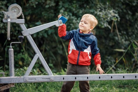 The curious little boy researching boat trailer clutch system in nature foliage background.