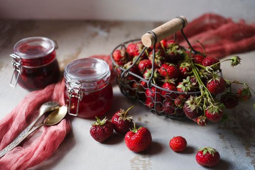 Summer breakfast concept with srawberry jam and fresh harvested berries in a basket. Still life, selective focus