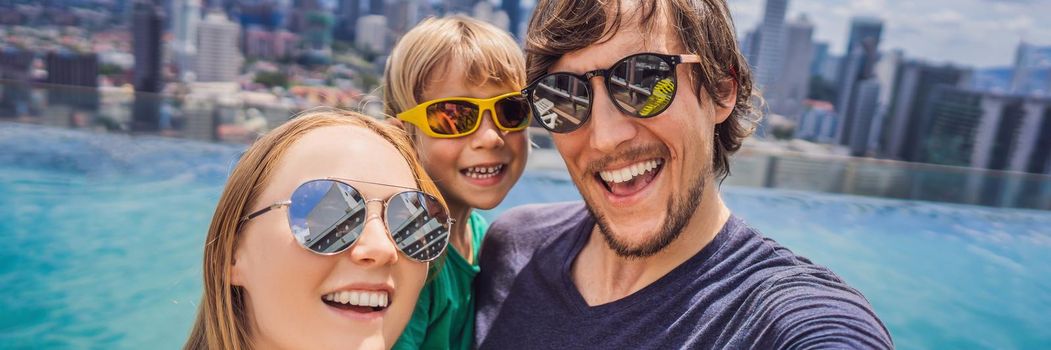 Vacation and technology. Happy family with kid taking selfie together near swimming pool with panoramic views of the city. BANNER, LONG FORMAT