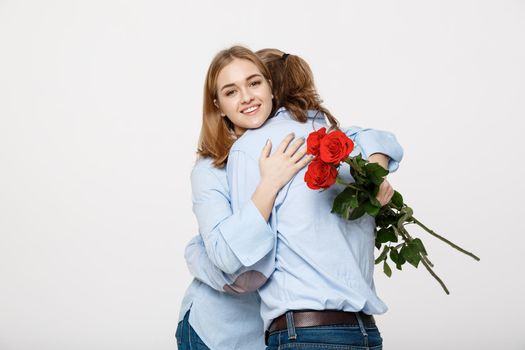 Portrait of an attractive young man hiding flowers from his girlfriend before giving her a surprise over white isolated background .