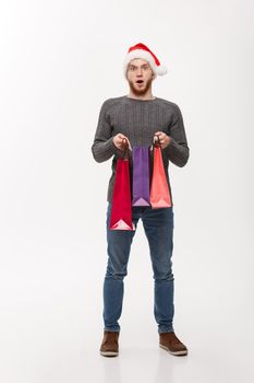 Christmas Concept - attractive young caucasian man surprising shocking gift in shopping bag.