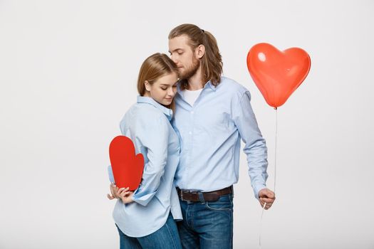 Portrait of young man and woman holding a heart- shaped balloon and paper.